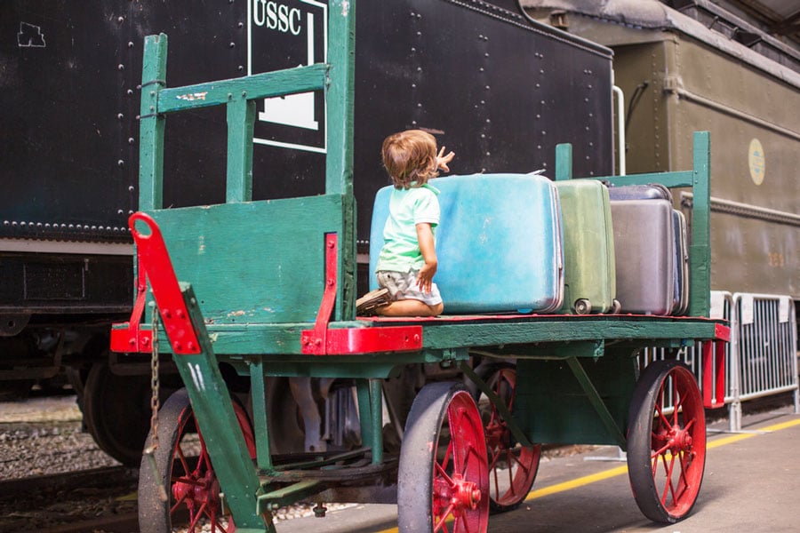 View of a child sitting on a luggage cart in Gold Coast Railroad Museum