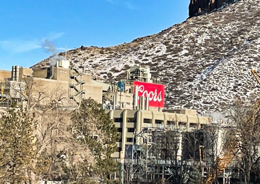 View of red signage of Coors and factory of The Coors Brewery