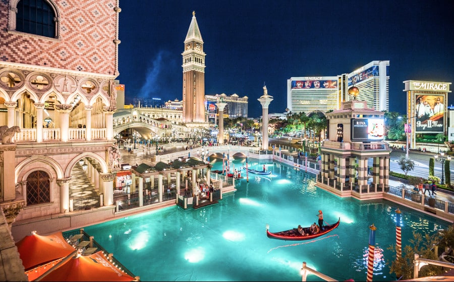 Gondolas sailing at the illuminated Venetian at night in Las Vegas