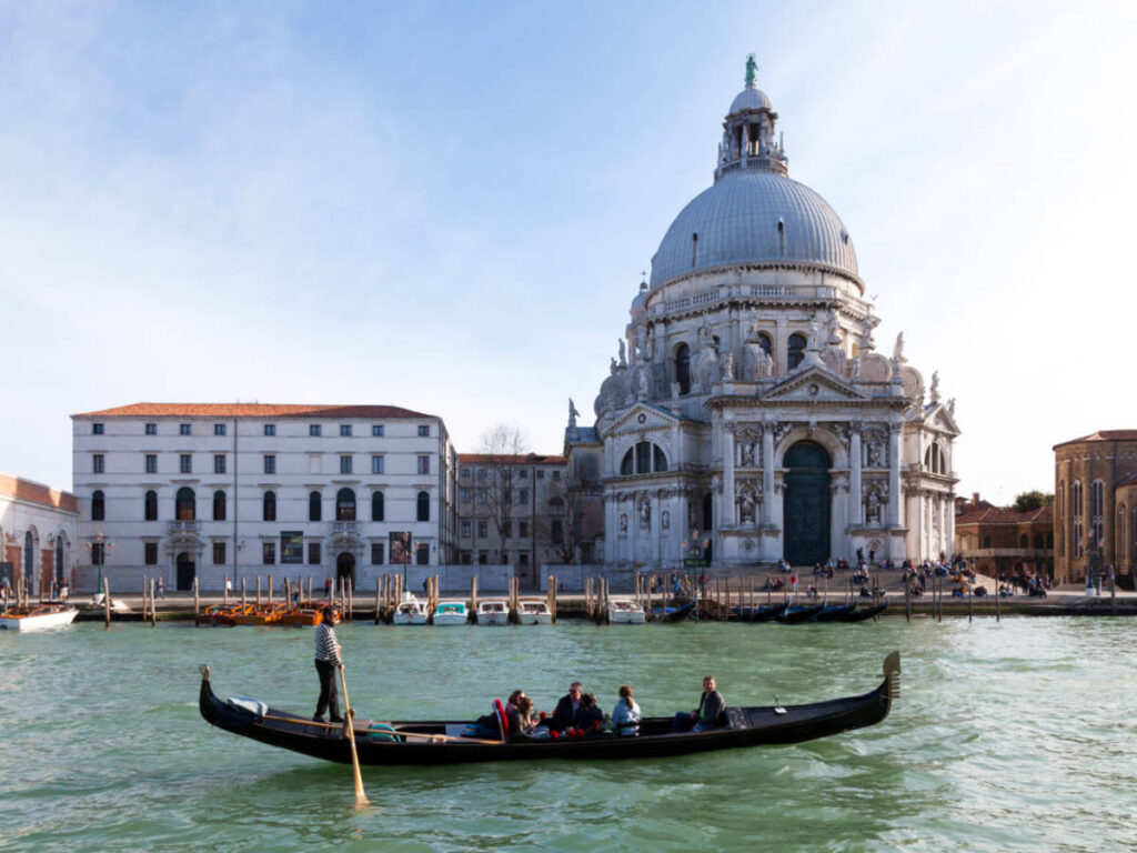 View of the tourists riding the gondola in Venice with the great architecture in the background