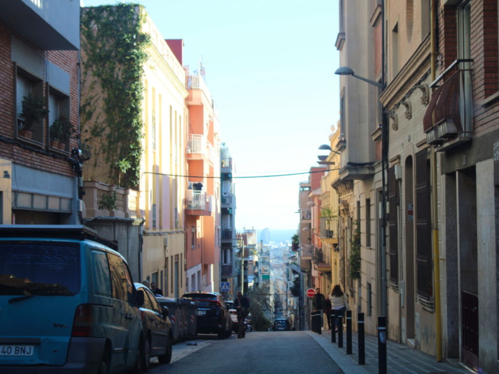 People walking and cars parked along the side of Gràcia streets