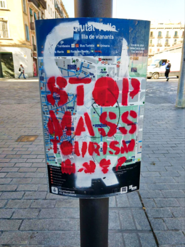 A graffiti of "Stop Mass Tourism" on a post in in Barcelona