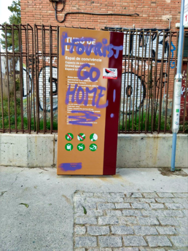 A graffiti of "Tourist Go Home!" on a signage in in Barcelona