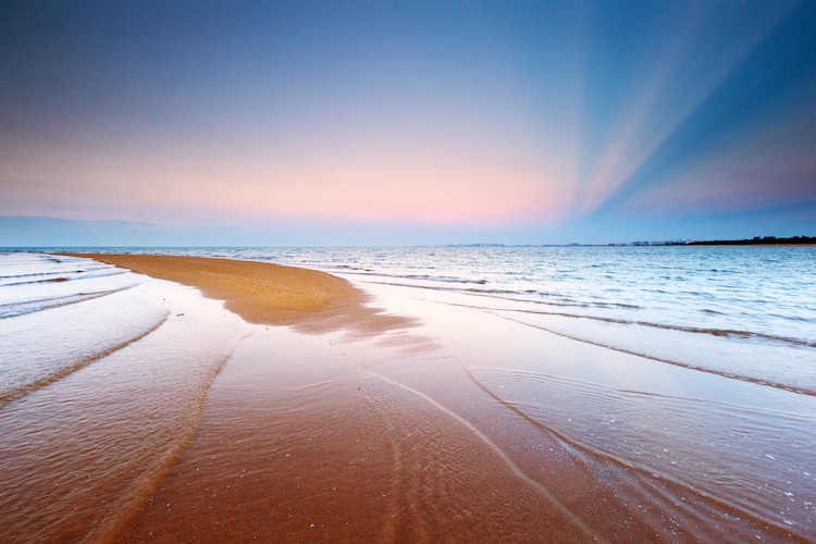 Water laps along the shoreling in Grand Beach, Manitoba at sunset