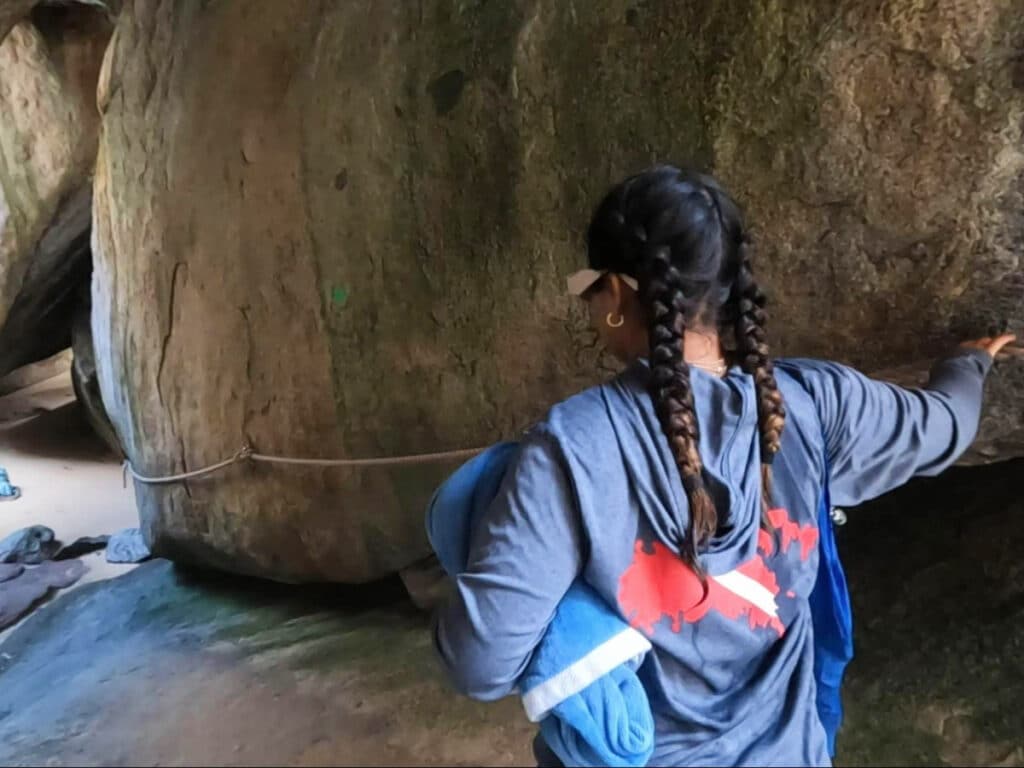 A girl entering a tunnel mad by  granite boulders 