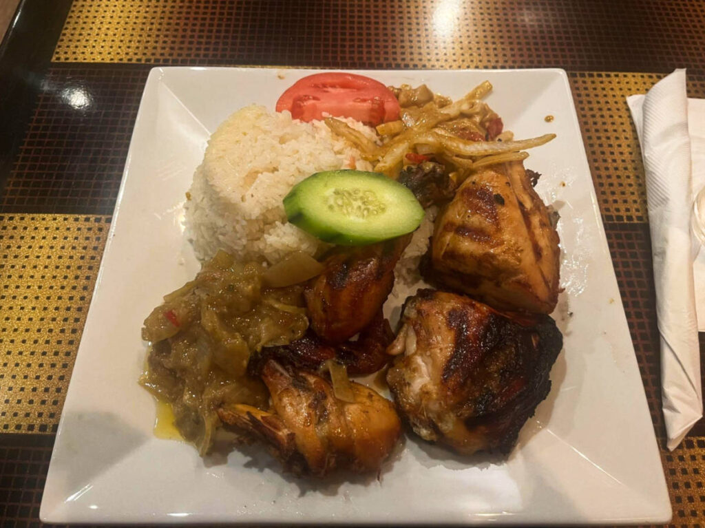 A plate of grilled chicken with onions and a cup of rice