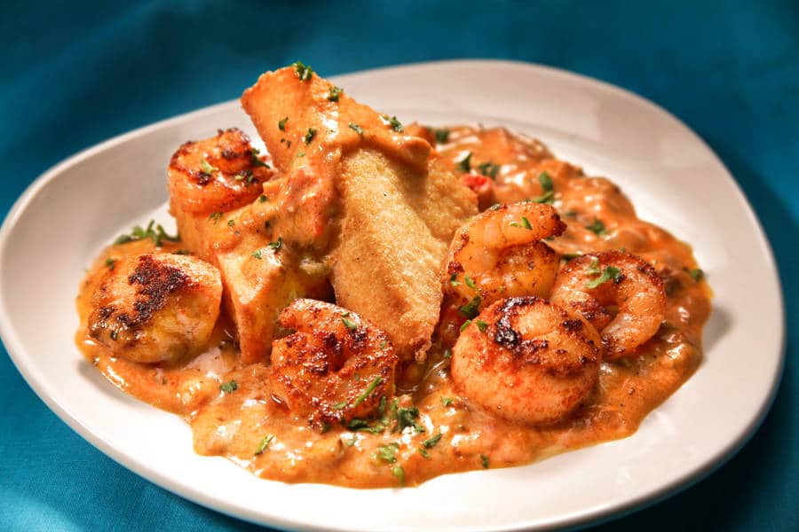 Closeup view of a plate with Grit Cakes, shrimps and scallops