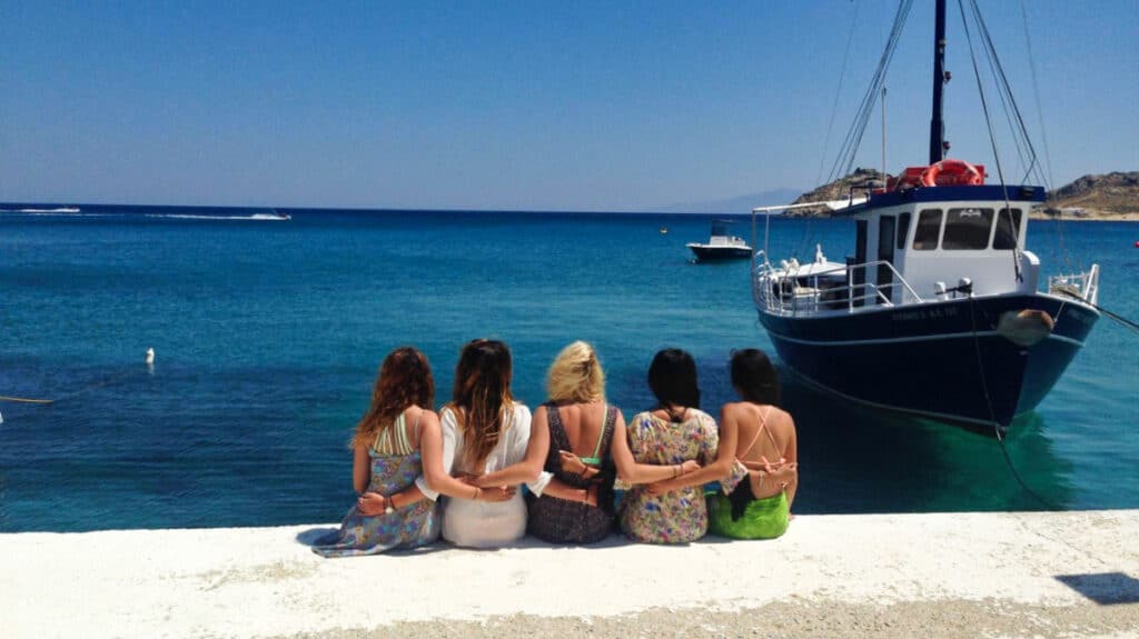 A group of friends posing on the waterfront with a docked boat