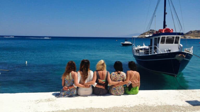 A group of friends posing on the waterfront with a docked boat