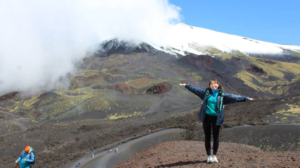 The author Lea Rose Allbaugh, posing for a photo with the Mount Etna in the background
