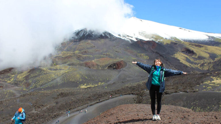 The author Lea Rose Allbaugh, posing for a photo with the Mount Etna in the background