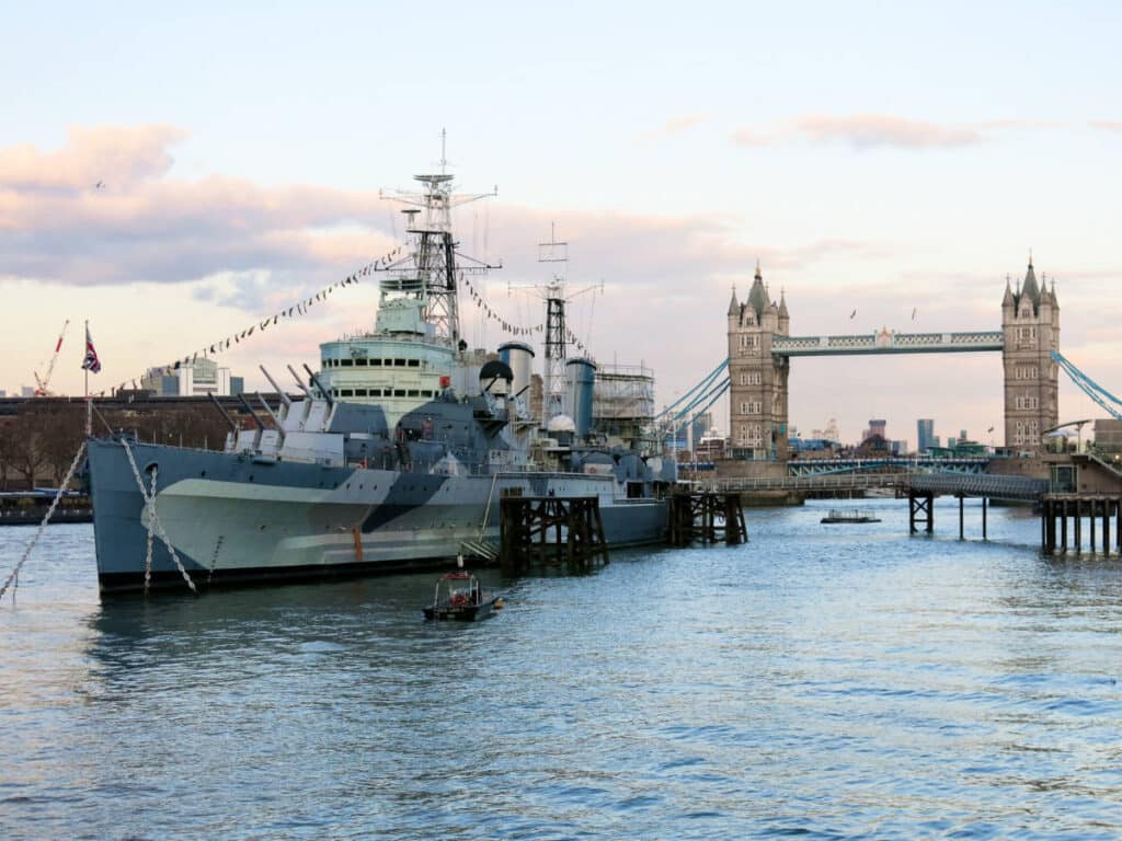 View of the HMS Belfast from the Thames with the Tower Bridge in the background at sunset