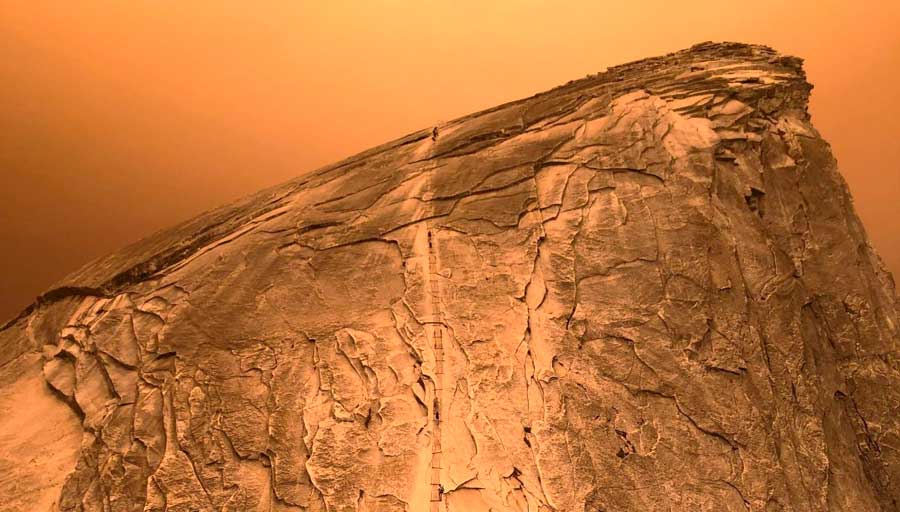 People climbing the Half Dome in Yosemite National Park during a wildfire