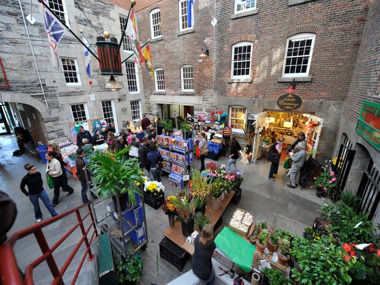 View of people on a market with buildings and plants