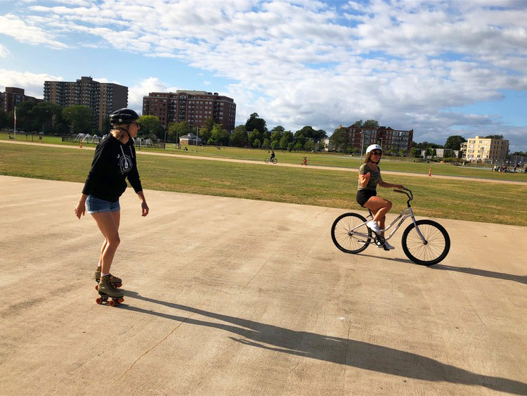 Girl riding a bike and other girl skating on oval