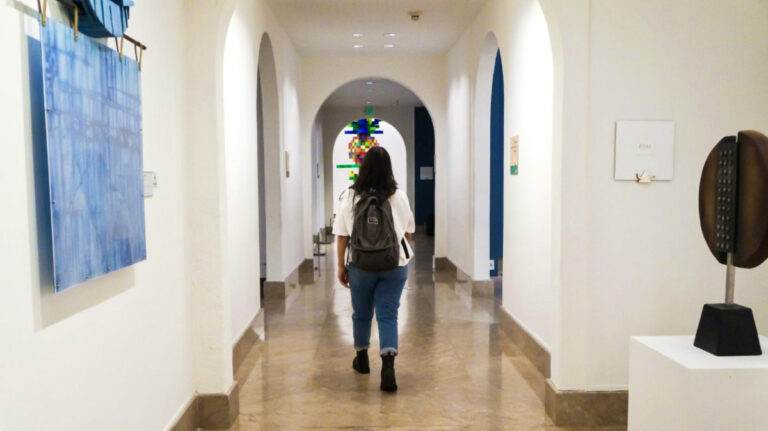 The author Vanessa Ramos, walking along the hallways with arch doors inside a museum