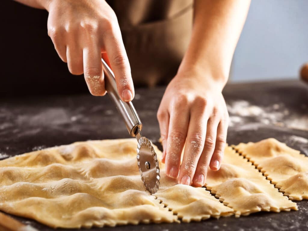 Closeup look of the a woman's hands cutting the ravioli