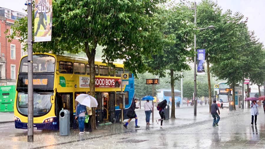 View of the people getting on and off the yellow double decker bus under the heavy rain in Dublin