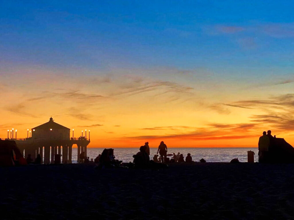 View of the silhouette of the beachgoers setting up their camping tents at sunset