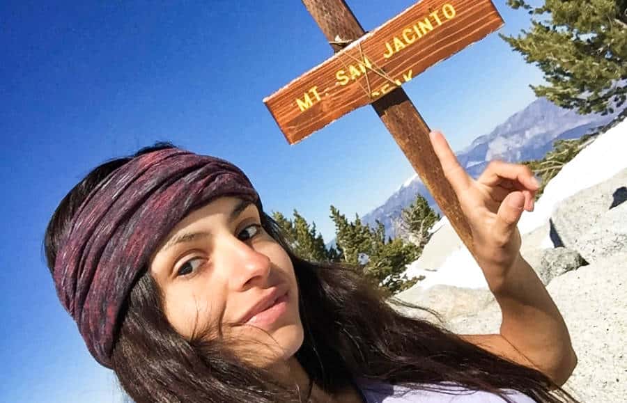 The author (McKenna Mobley) takes her own portrait with the one broken wooden sign of Mt. San Jacinto.