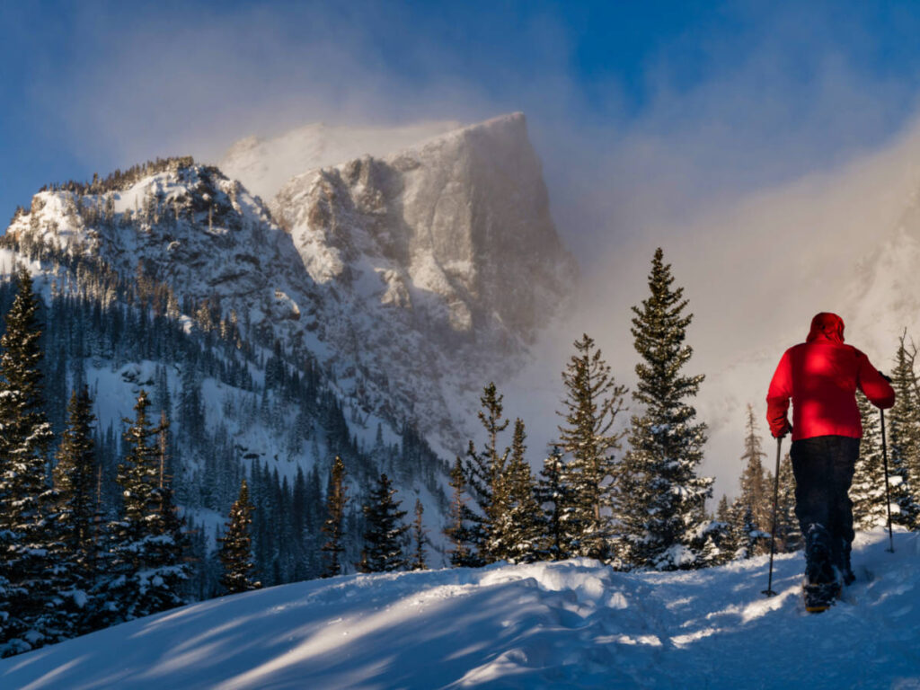 A hiker snowshoeing in Rocky Mountain National Park with magnificent mountain views in winter