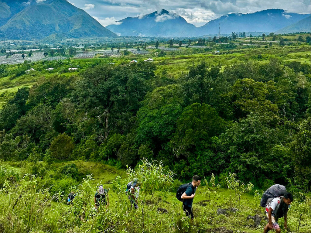 A group of hikers trekking through the low hills surrounded by greenery