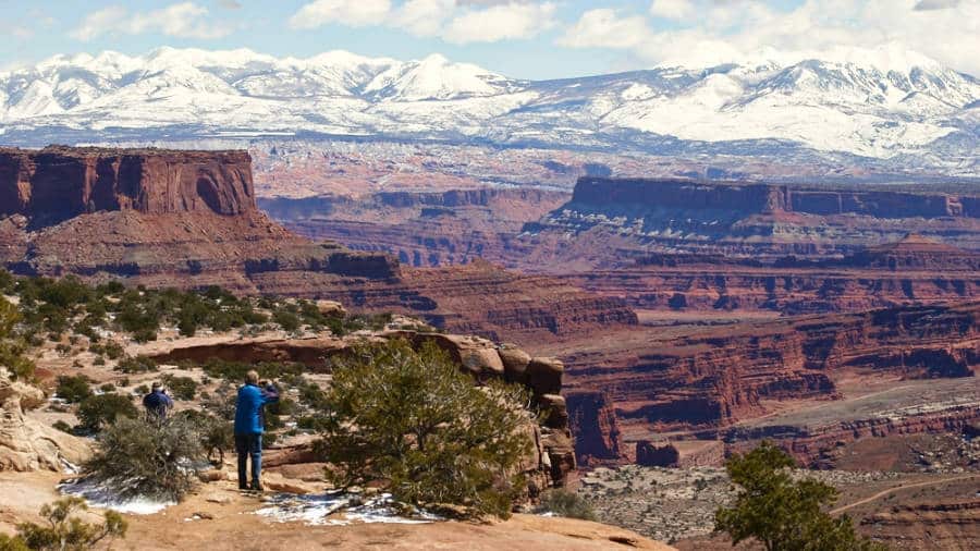 Hikers enjoying the scenic view of snow capped Canyonland National Park