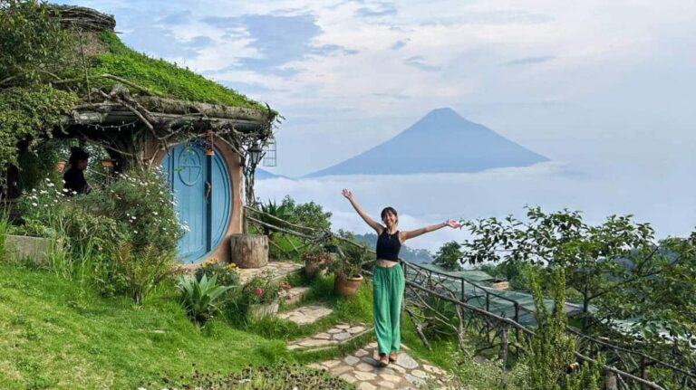 Author Lea Rose posing for a photo with a volcano on her background at the Hobbitenango in Guatemala