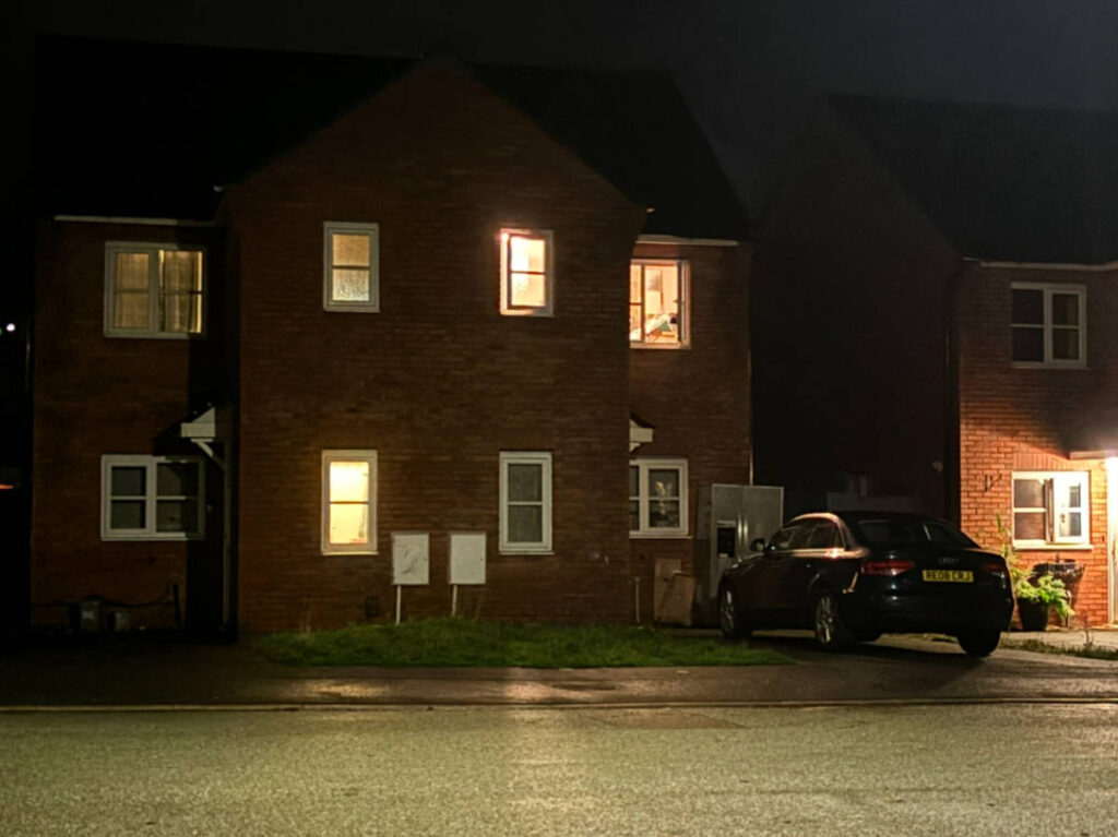Home in the UK with windows wide open without shades at night