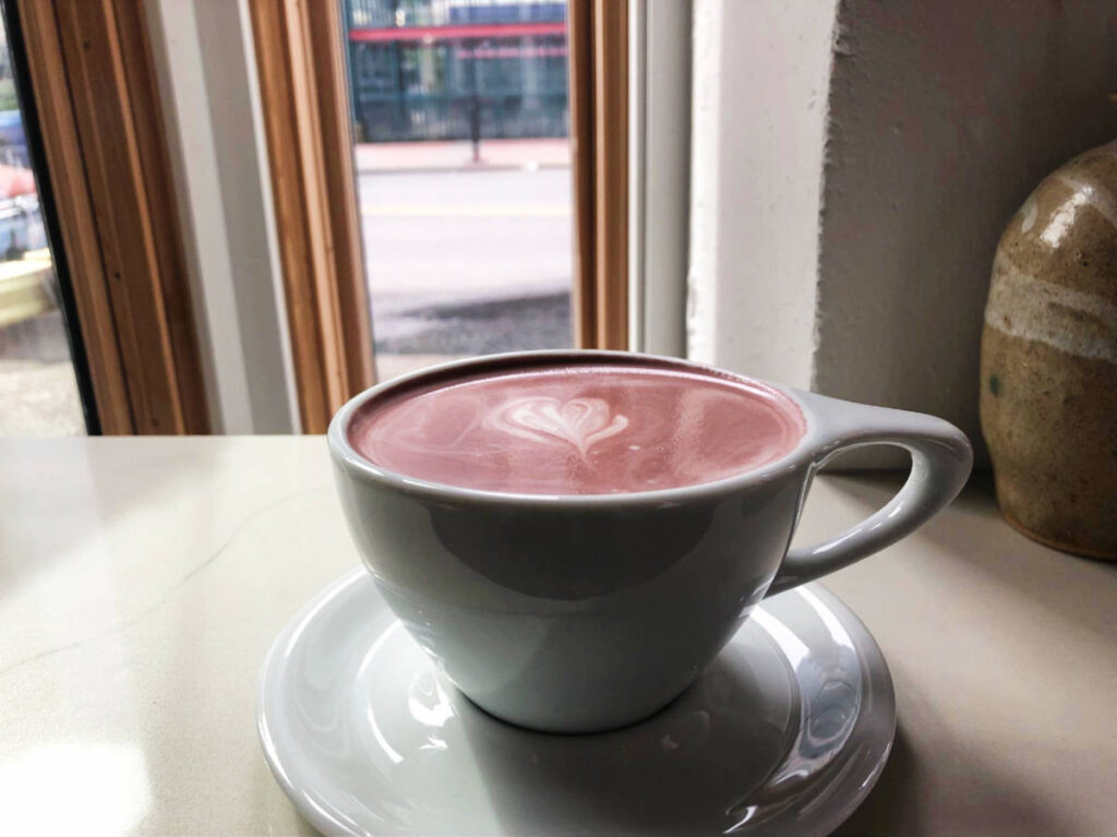 A cup of purple ube latte served in Hood Famous