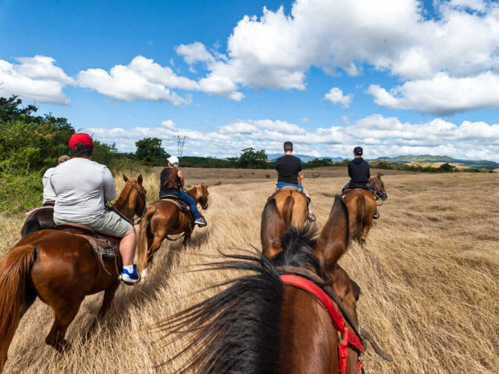 A group of people on a horseback riding in the field