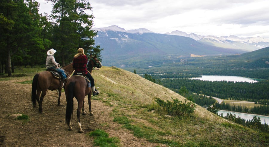 Two people enjoy the scenic view while horseback riding in the high sierras.