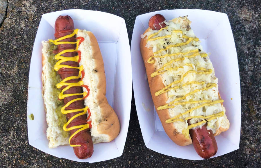Two hotdogs in a bun topped with mustard