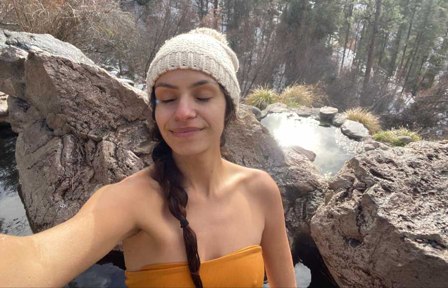 The author taking a selfie with a hot spring on her background during winter