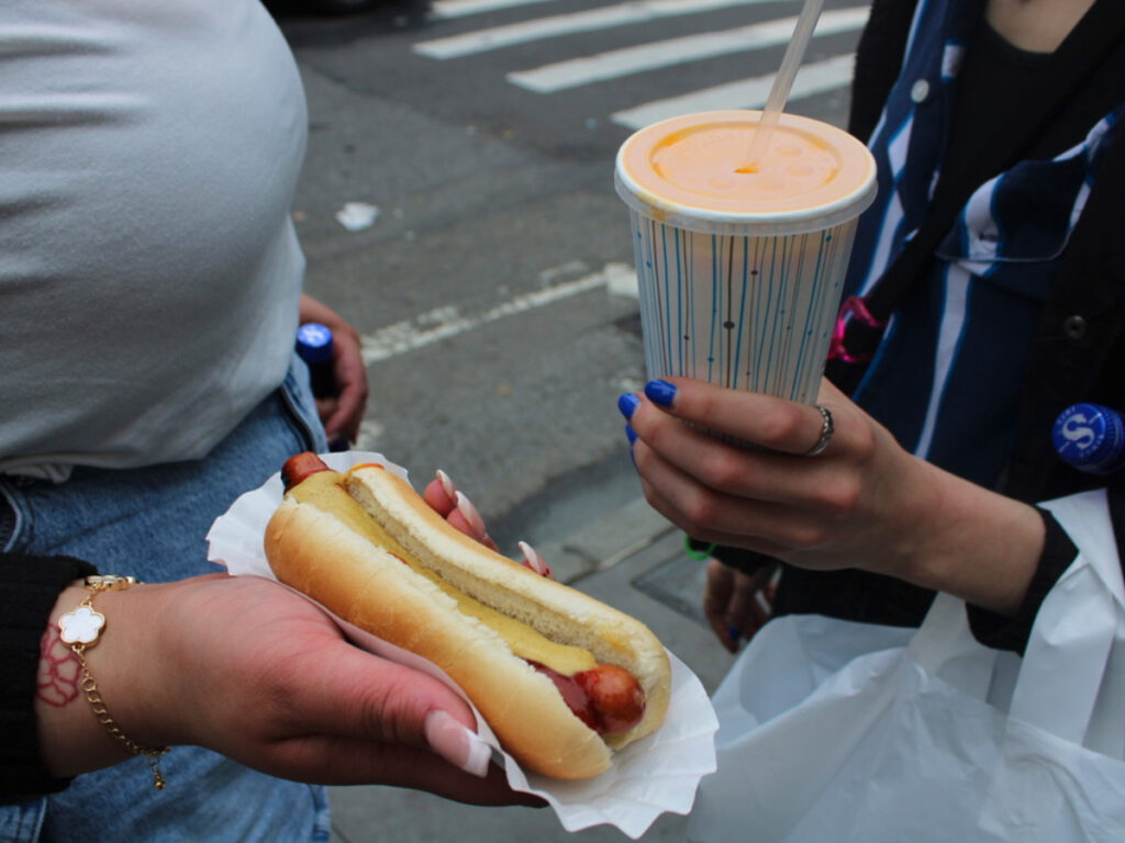 Holding the Hot dog and papaya drink from Gray’s Papaya