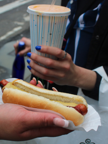 Hands holding a hot dog bun and drink
