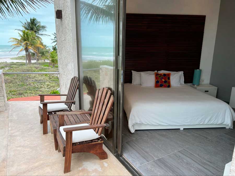 View of the bed from the bedroom and chairs from the balcony in Hotel La Casa Cielo