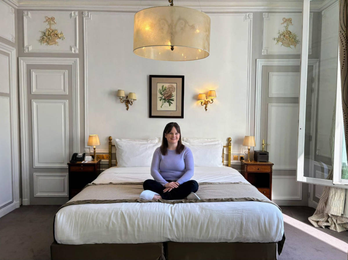 The author Rachel Kapelke-Dale sitting on her bed in Hotel Regina Louvre