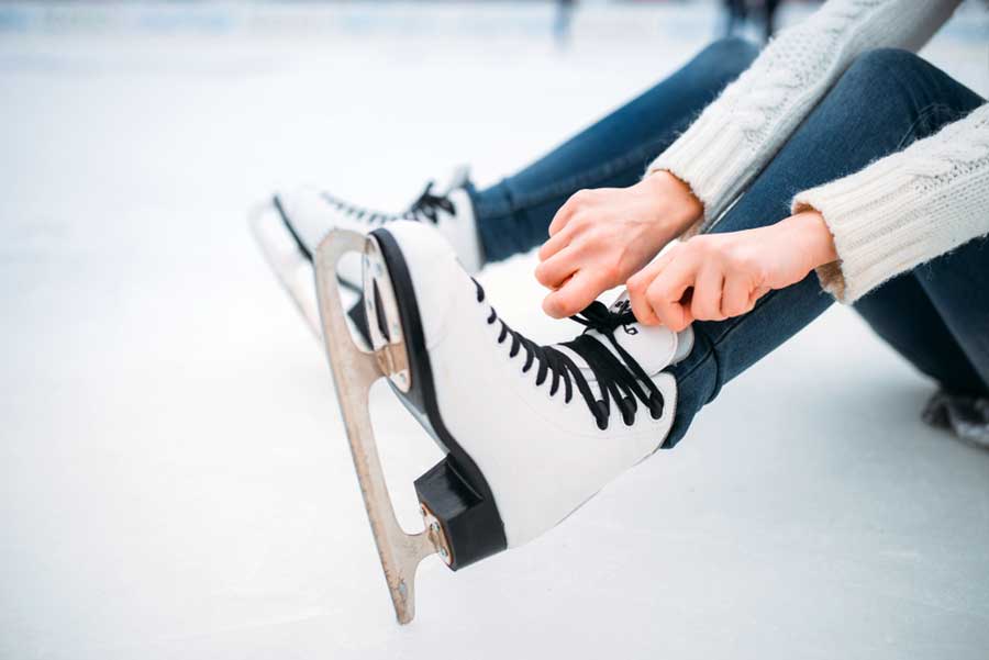 A woman tying her ice skates shoelaces