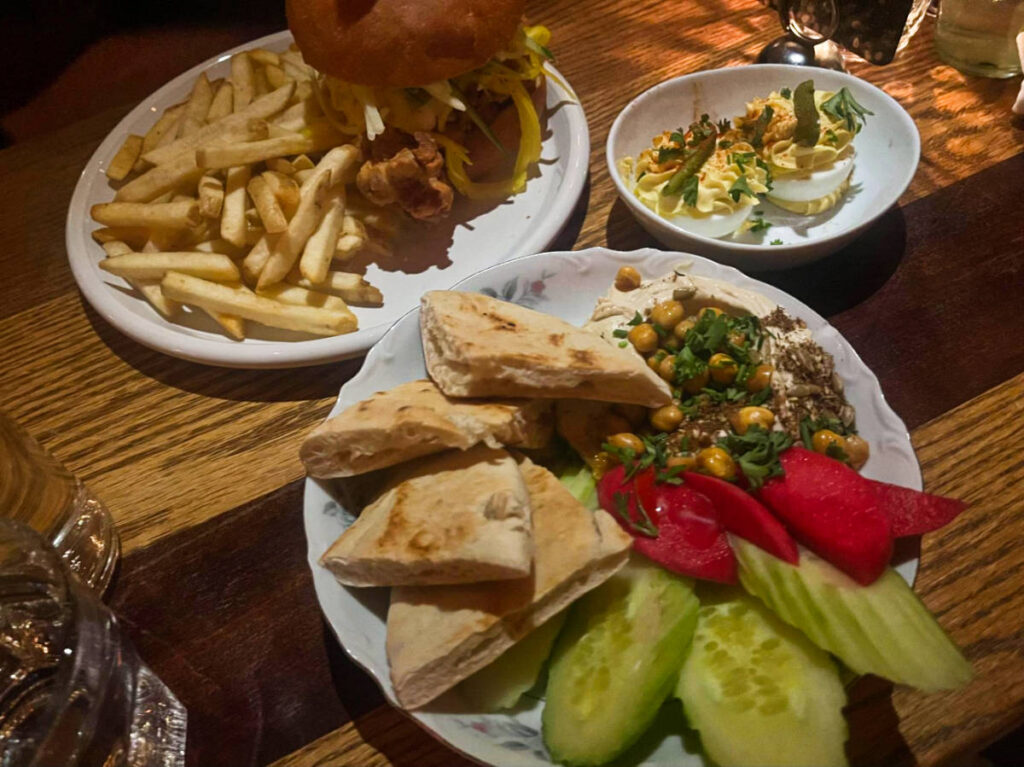 A hummus platter, deviled eggs, and a fried chicken sandwich with fries from FERNS