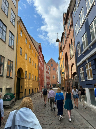 Group of people walking thru a street with colorful buildings