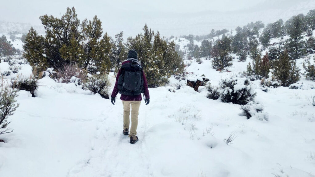 The author, Abigail, walking on the snow covered landscape while using the Hyperlite Mountain Gear Southwest Backpack