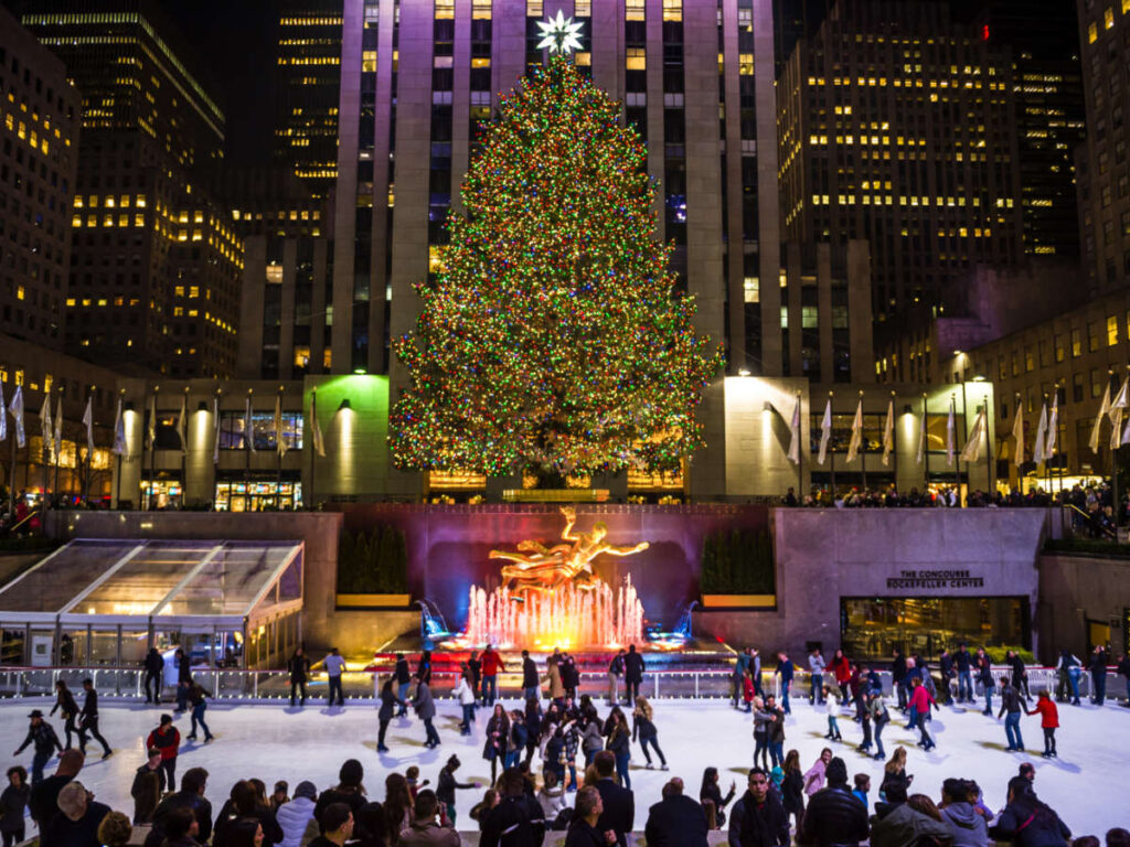 View of the ice skaters on the rink with the huge Christmas tree in the background