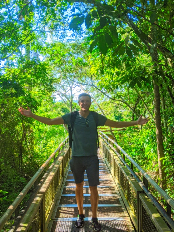 Nate Hake with arms outstretched on the trails, surrounded by foliage