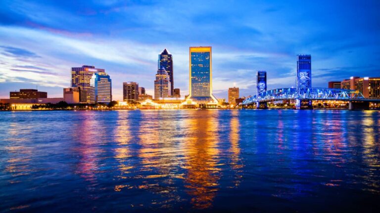 Panoramic view of the illuminated Jacksonville skyline reflecting on the water at dusk