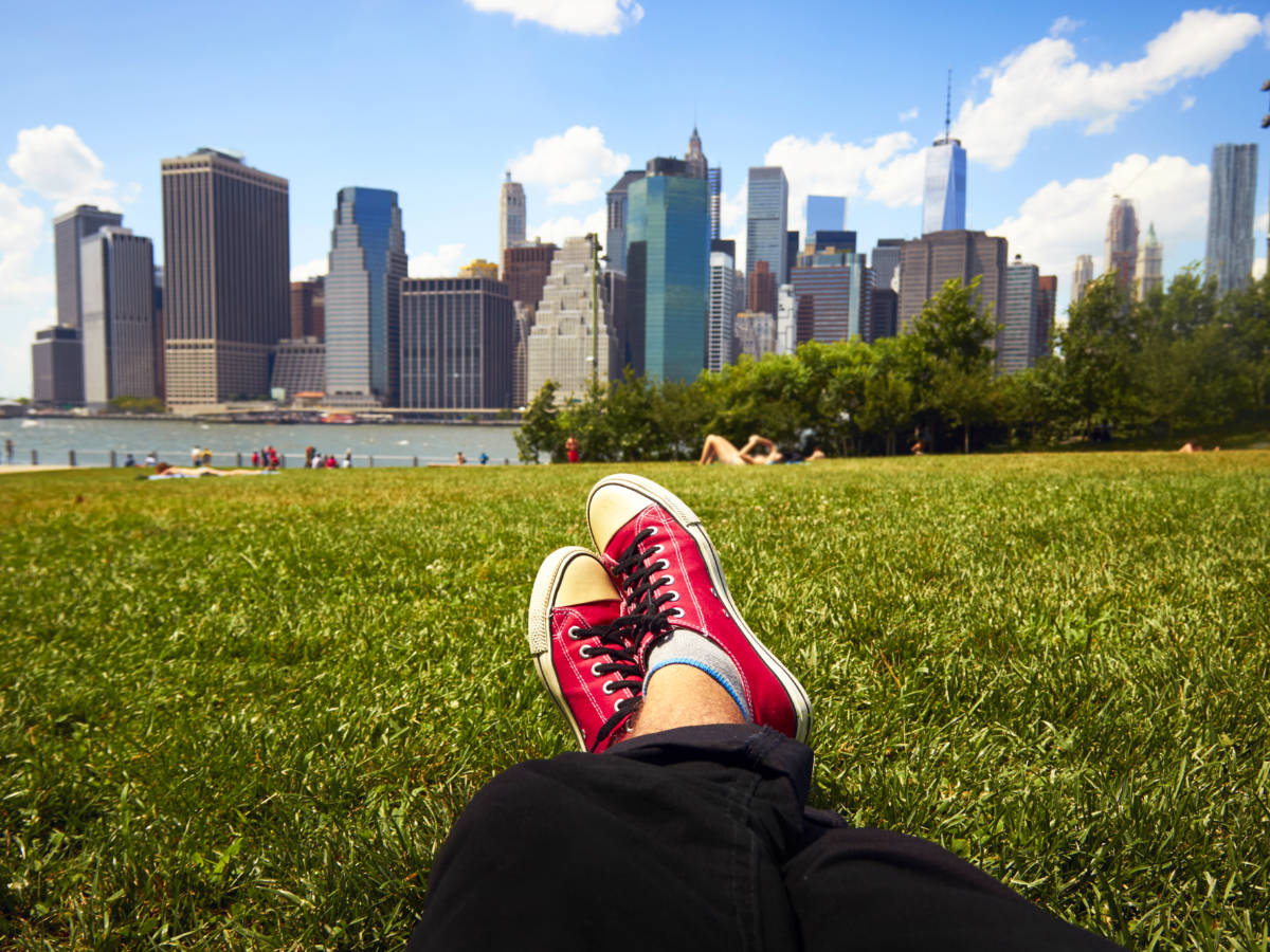 Feet in red sneakers on the grass in front of Manhattan