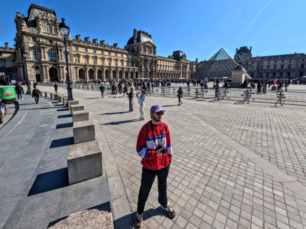 A man standing in front of the Louvre Museum