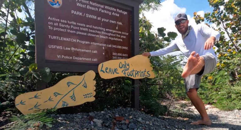 The author Andrew Bloem posing for a photo with the information board of Sandy Point National Wildlife Refuge
