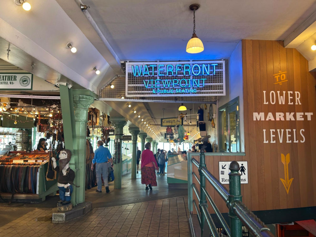 People wander inside The Pike Place Market with stalls and signs around