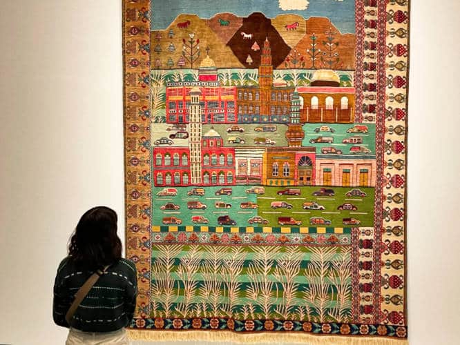A woman looking at the intricate textile from MCA’s exhibit